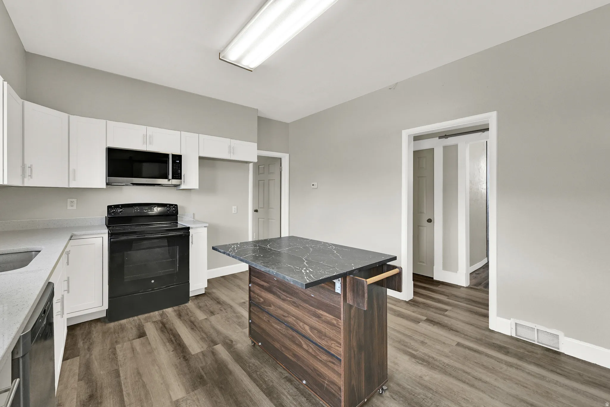 Modern kitchen featuring white cabinetry, a built-in microwave, and a black electric range