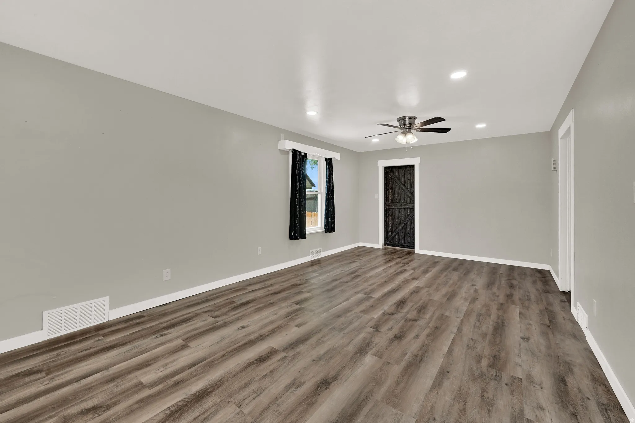 Spacious room featuring wood-finish flooring, recessed lighting, and a modern ceiling fan