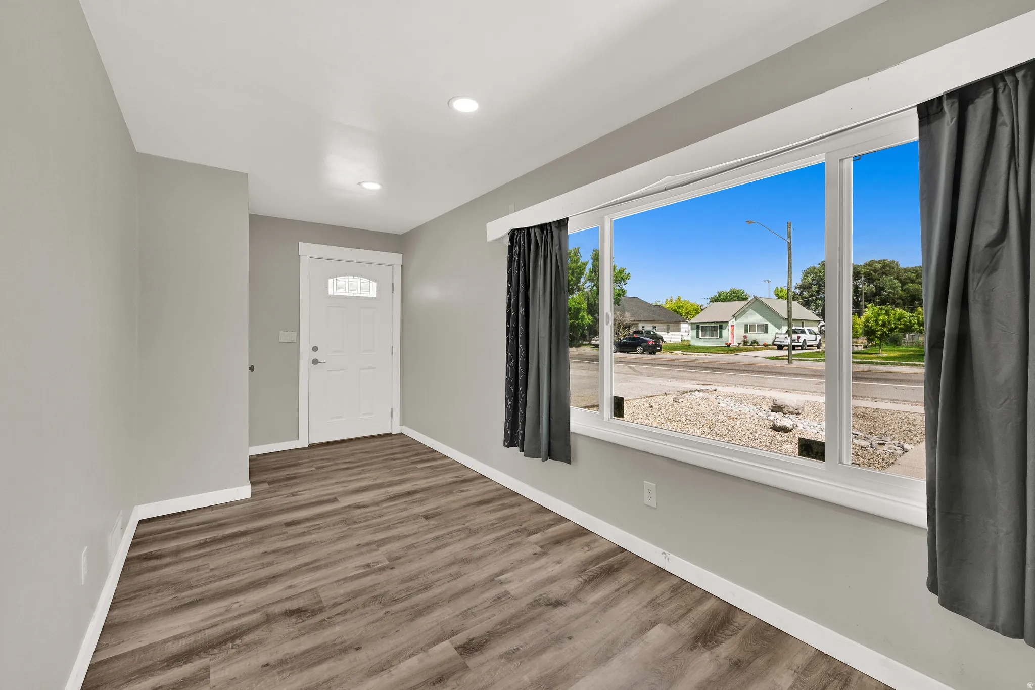 Inviting entry space featuring wood-finish flooring, recessed lighting, and a prominent front door with an arched glass insert