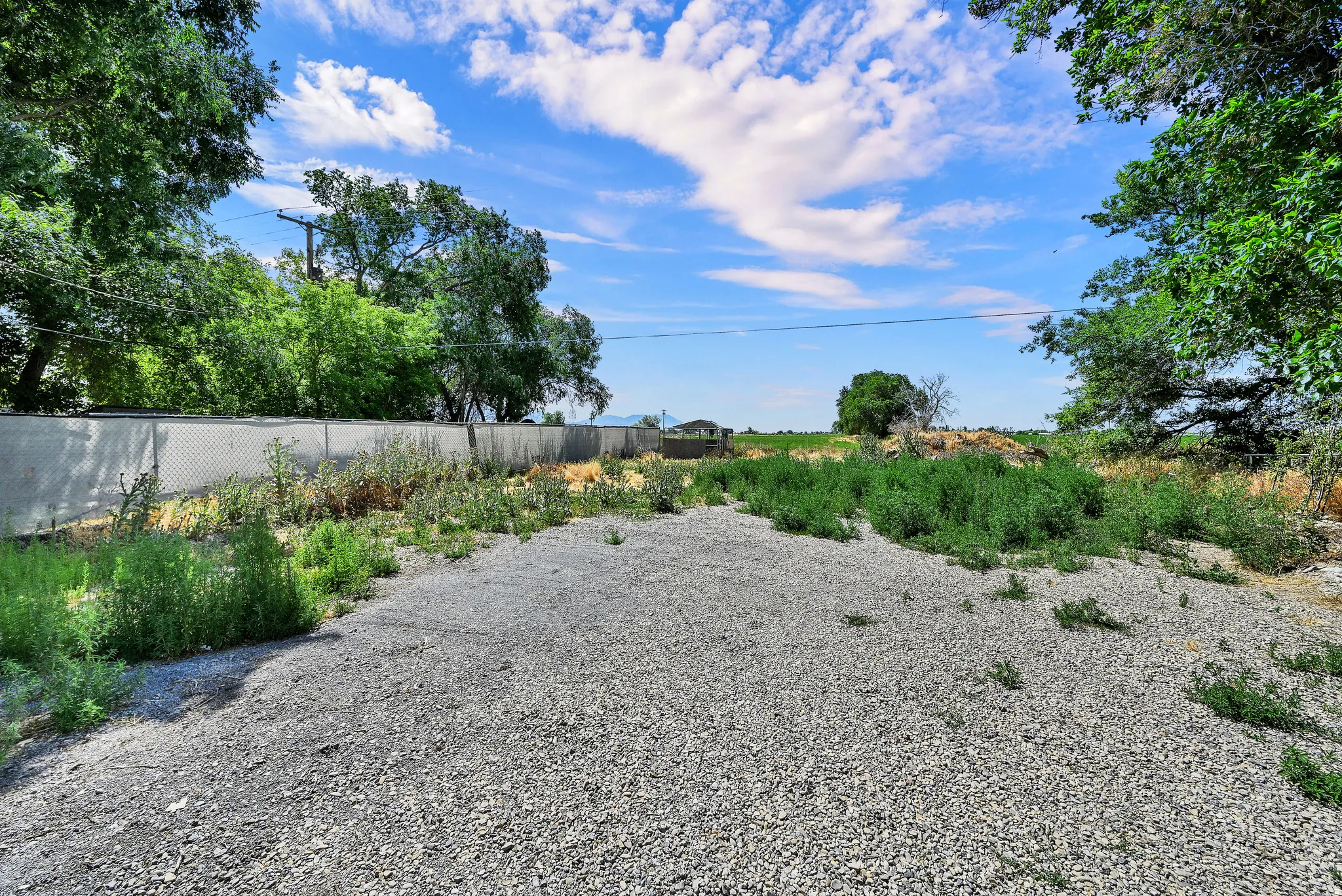 Gravel surface with surrounding foliage and a chain link fence