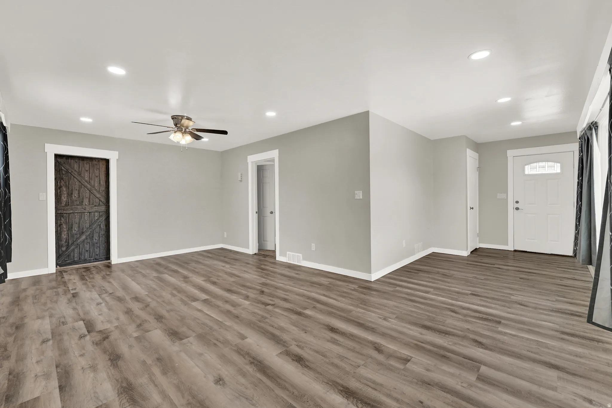 Spacious living area featuring wood-finish flooring, recessed lighting, and a ceiling fan