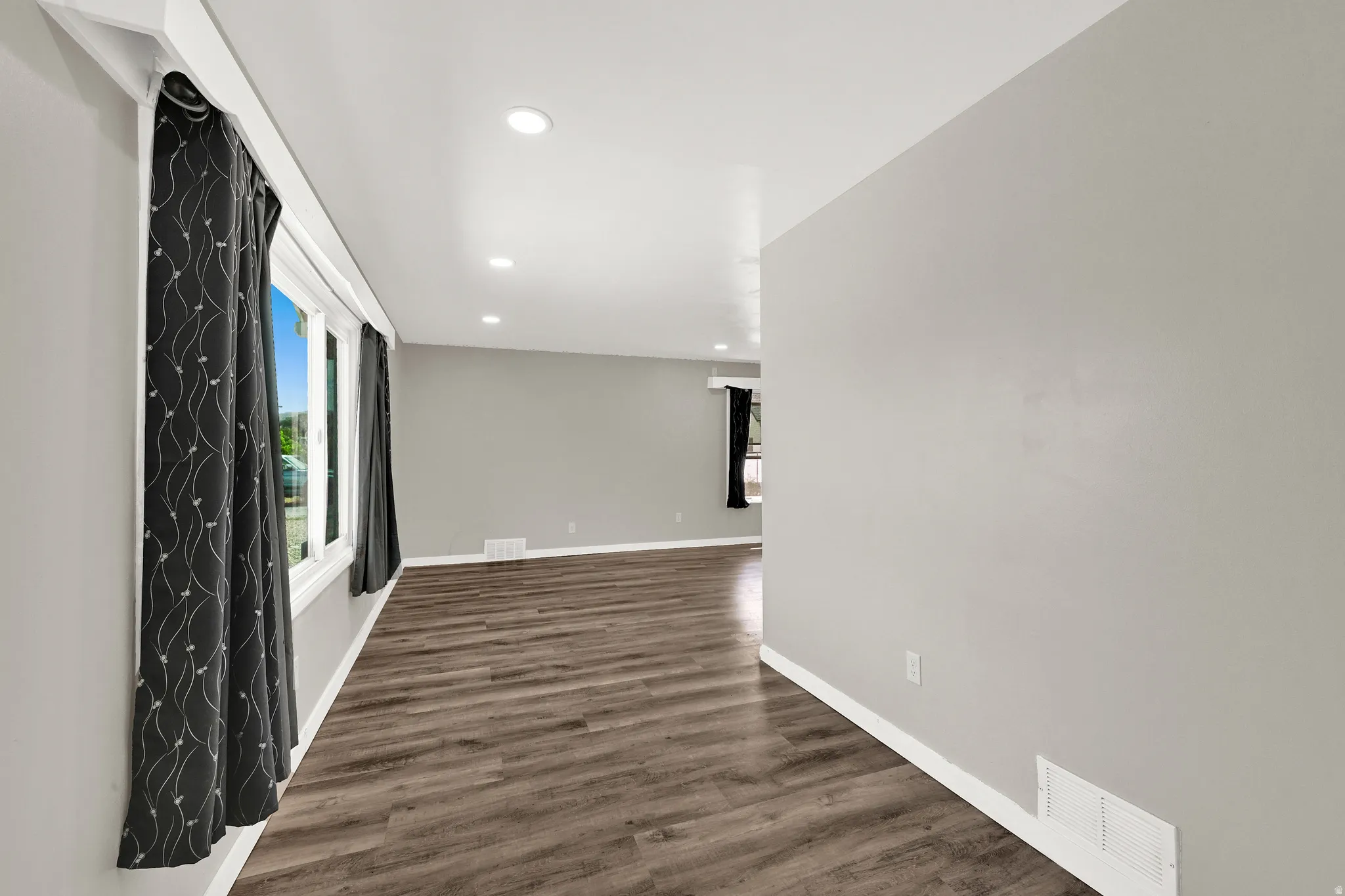 Spacious room featuring wood-finish flooring, recessed lighting, neutral wall tones, and white trim