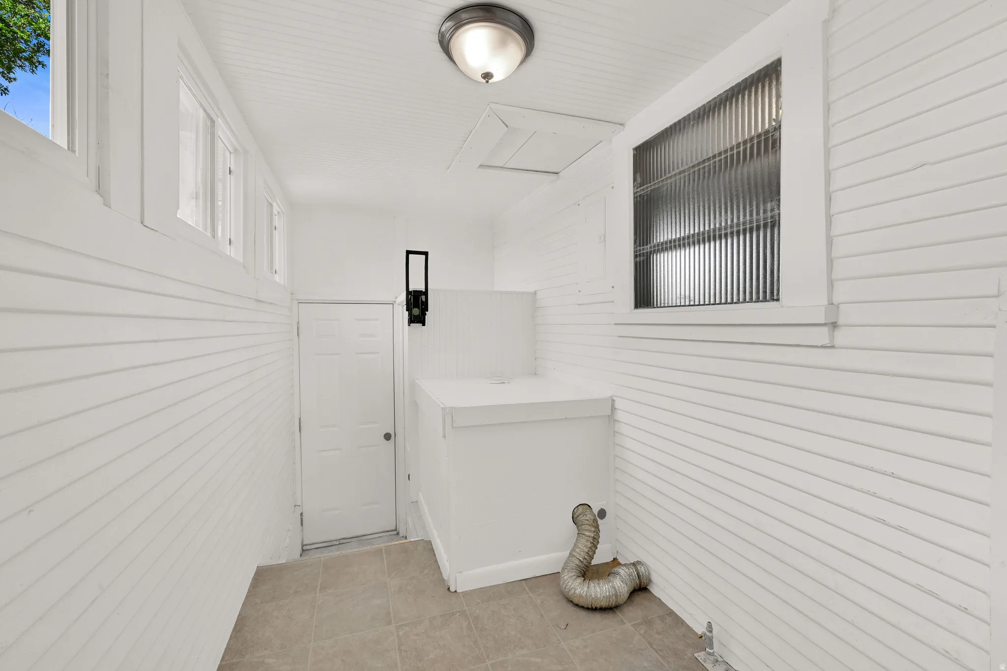 Utility room featuring white shiplap walls, recessed ceiling with beadboard, and neutral tile flooring