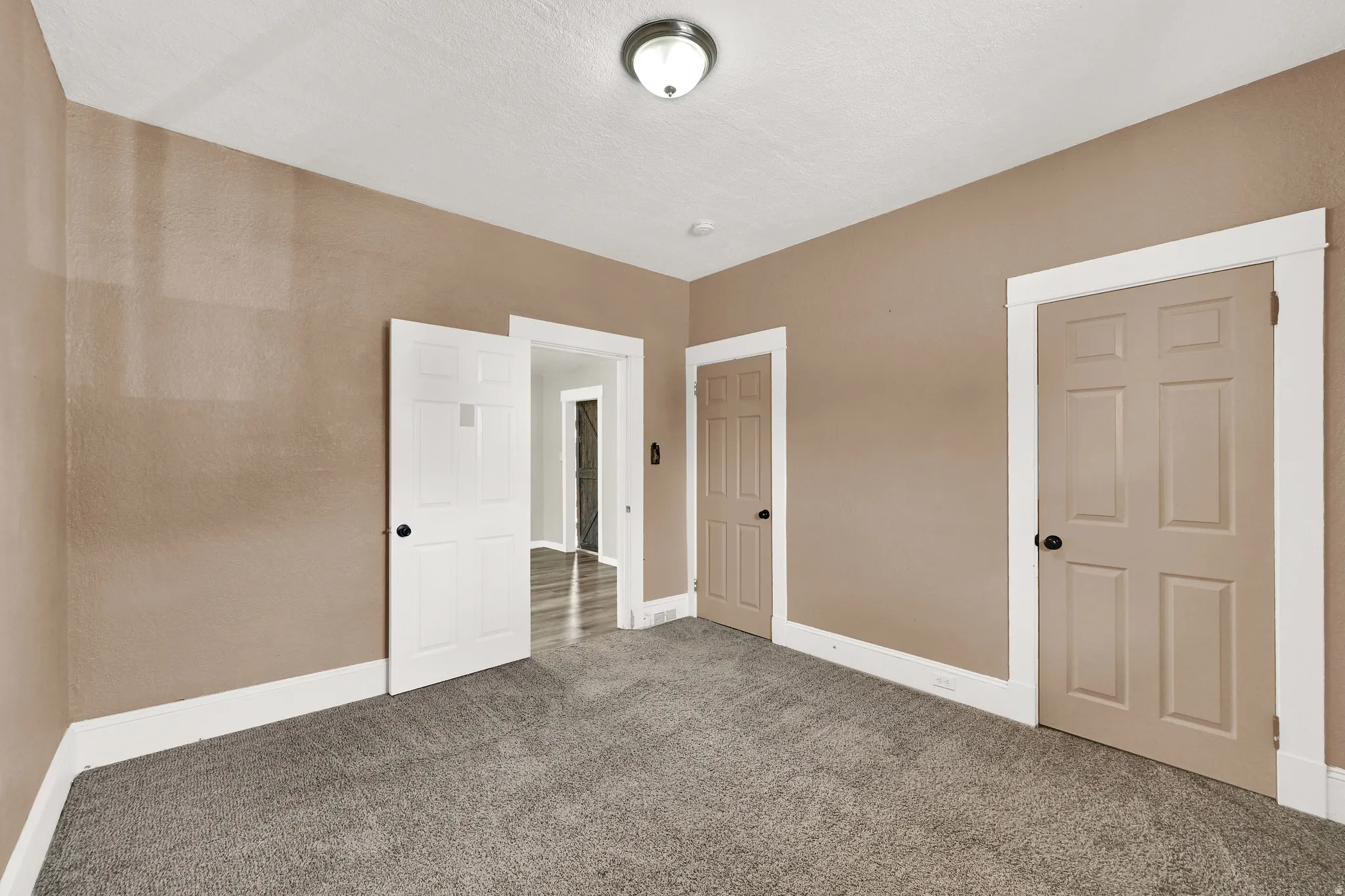 Carpeted room with neutral-toned walls, white baseboards, and white door trim