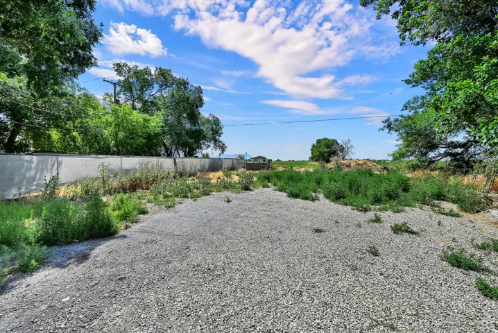 Gravel surface with surrounding foliage and a chain link fence