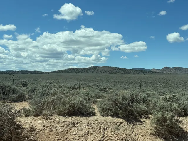 Expansive land parcel featuring natural desert flora, distant mountain ranges, and clear blue skies