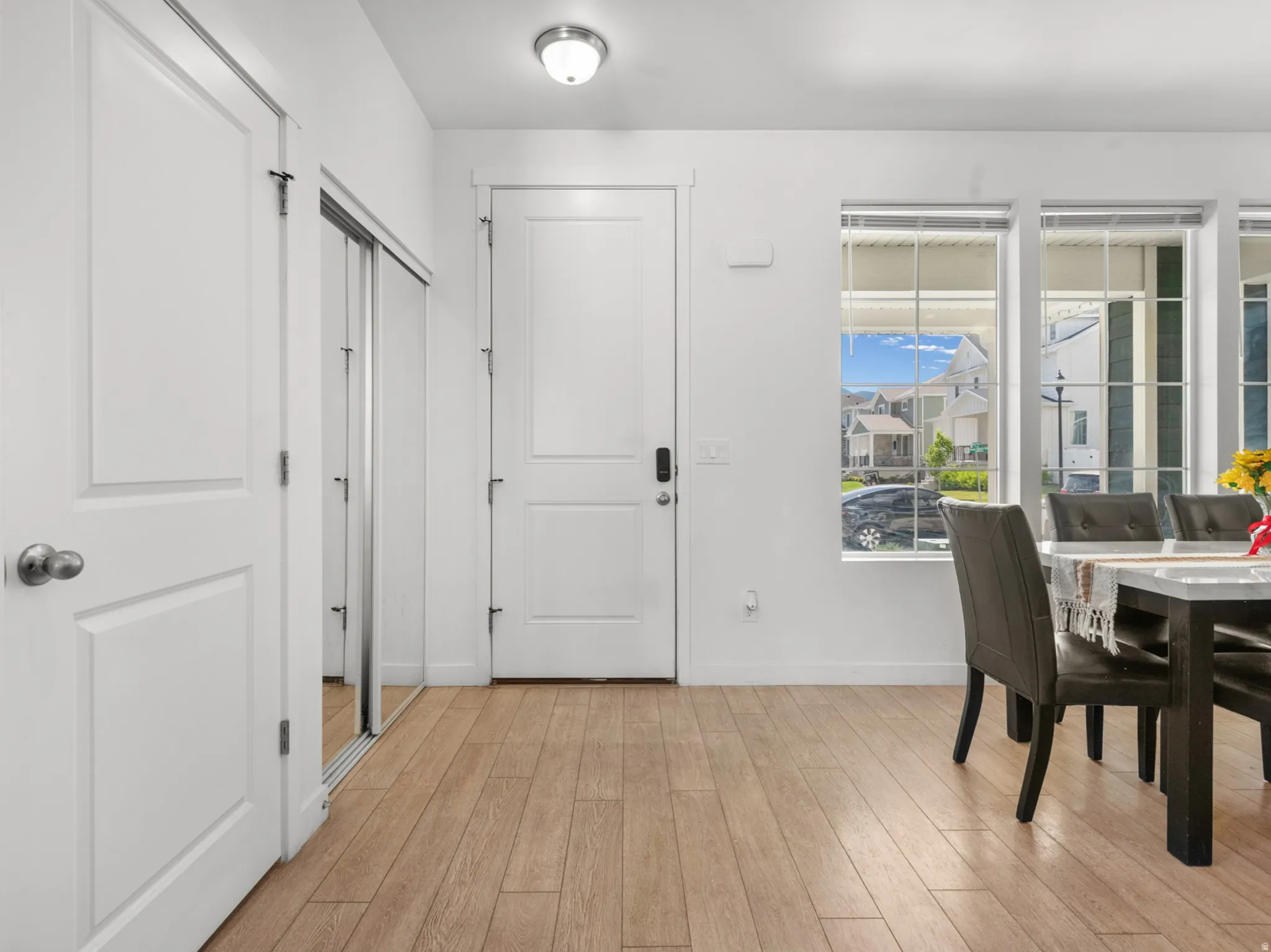 Entryway featuring wood-finish flooring, white paneled doors, and a mirrored closet