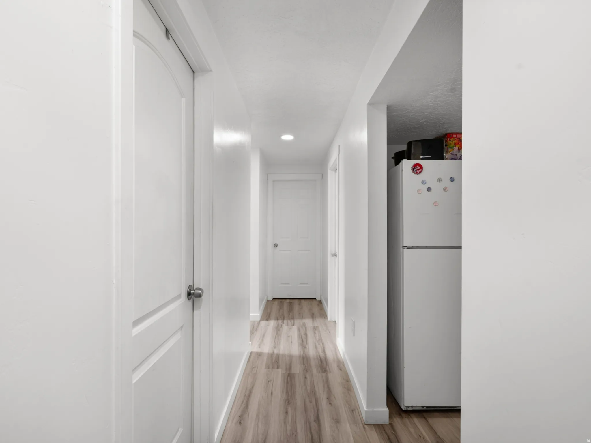 Hallway featuring wood-finish flooring, recessed lighting, and white paneled doors