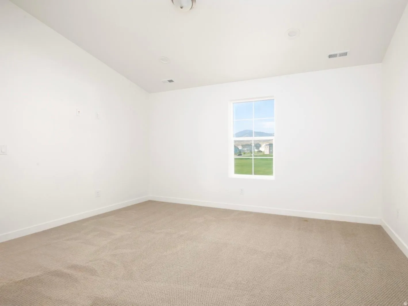 Spacious room featuring neutral carpeting, white walls, and a large window with a mountain backdrop