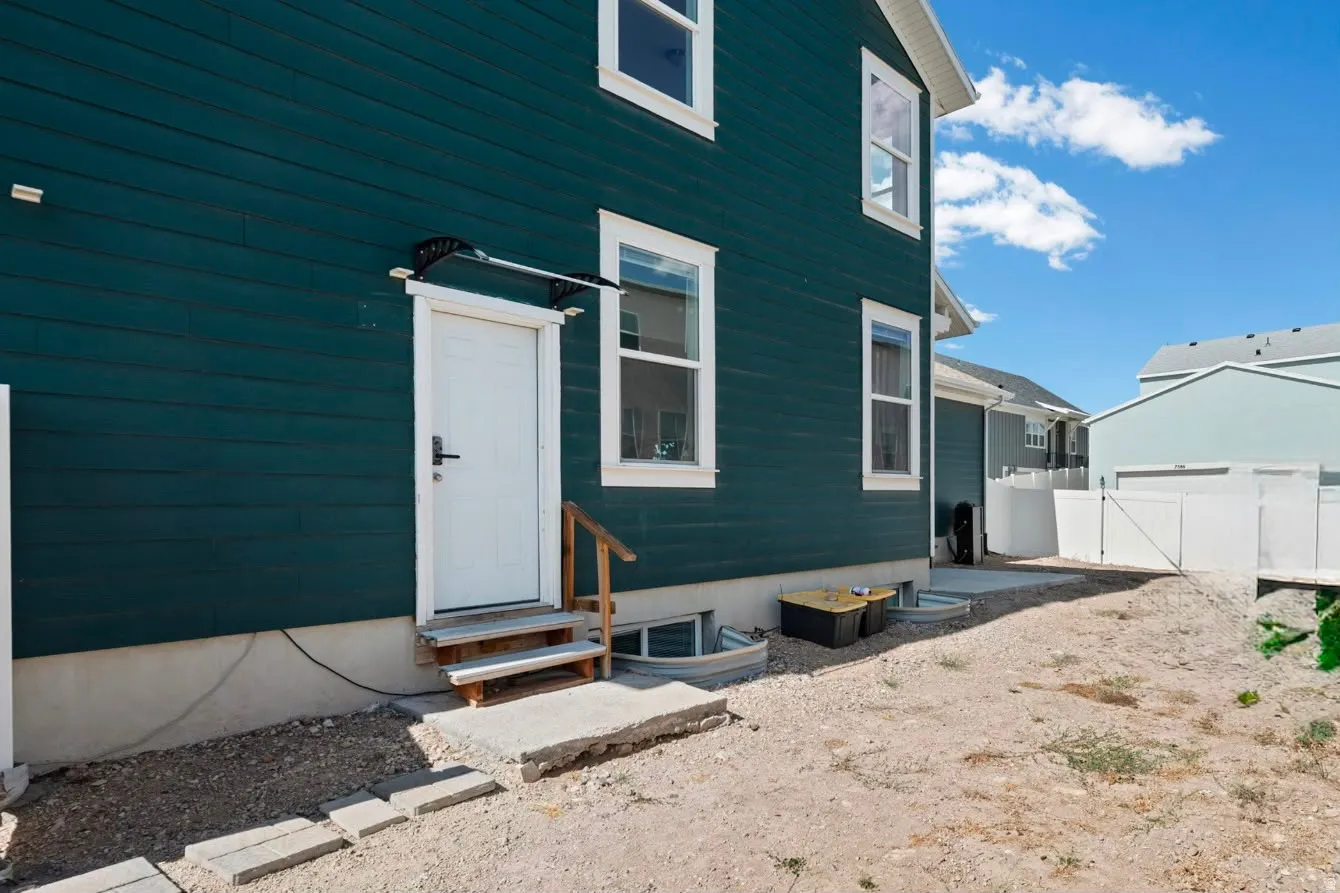 Dark teal horizontal siding with white trim windows and a white exterior door