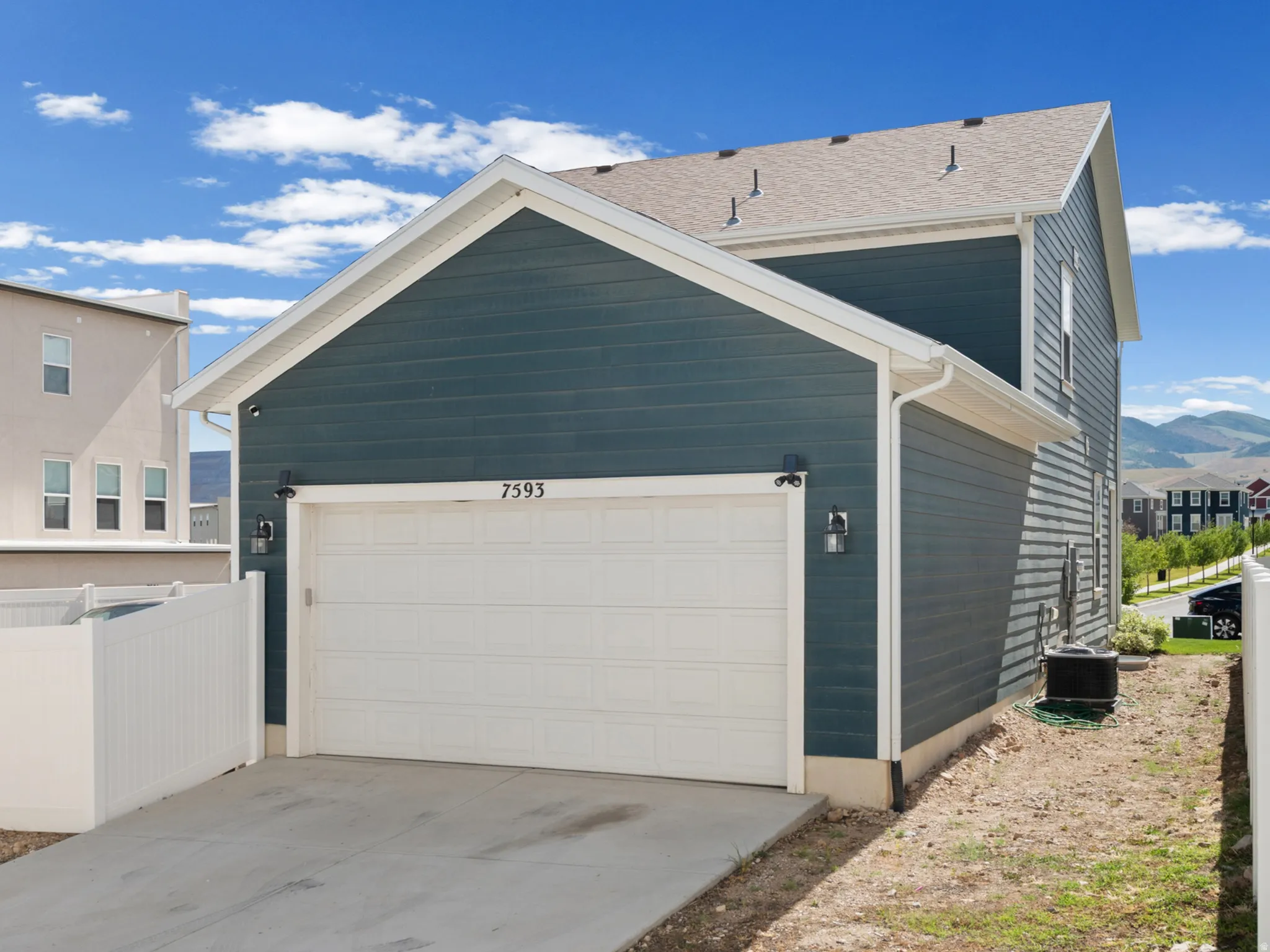 Attached two-story residence featuring a blue horizontal siding exterior and a white garage door