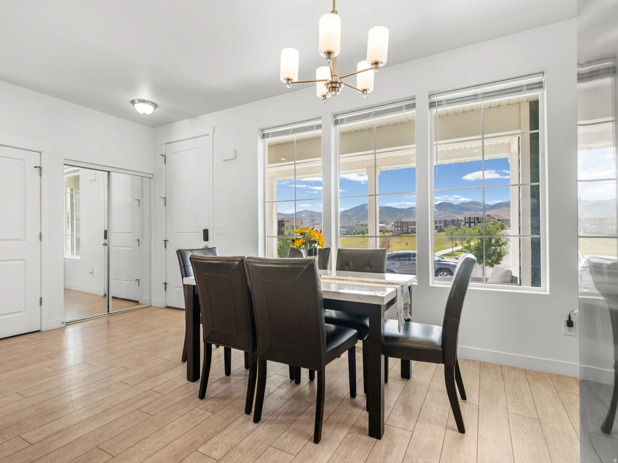Dining area featuring wood-finish flooring, a modern chandelier, and multiple windows