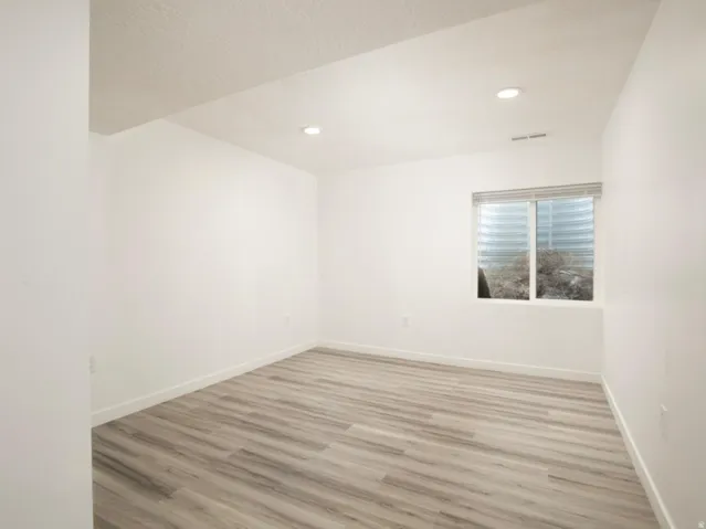 Bright room featuring wood-finish flooring, recessed lighting, white baseboards, and a window with blinds
