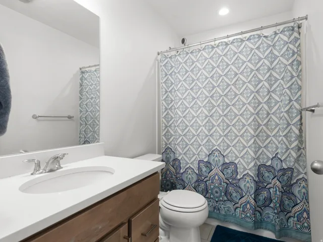 Bathroom featuring a single vanity with a white countertop, undermount sink, and chrome faucet