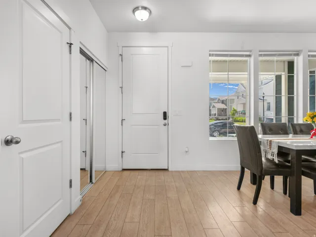 Entryway featuring wood-finish flooring, white paneled doors, and a mirrored closet