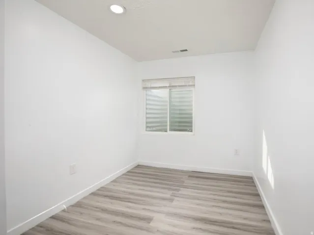 Room with wood-finish flooring, white walls, and a recessed ceiling light