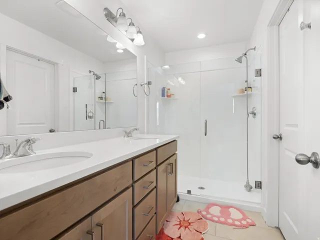 Bathroom featuring a dual vanity with light-tone cabinetry, white countertops, and chrome fixtures