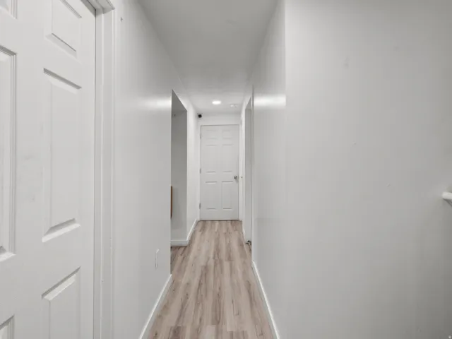 Hallway with wood-finish flooring, white walls, and recessed lighting
