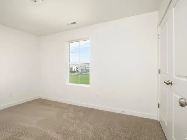 Light-filled interior featuring a single pane window, neutral-toned carpet, white painted walls, and white trim