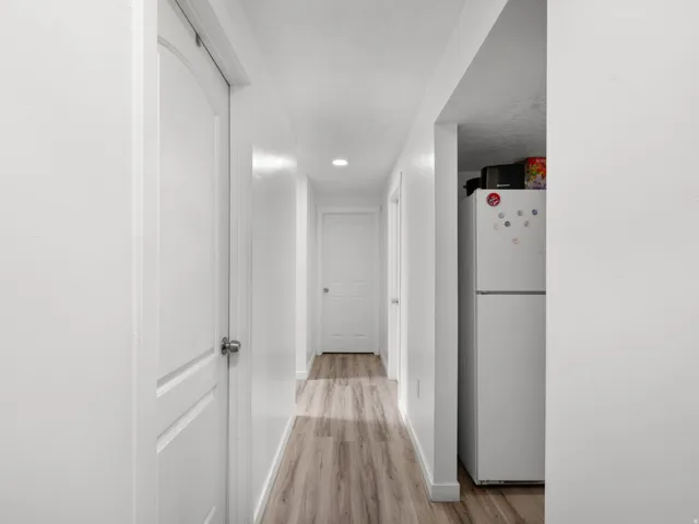 Hallway featuring wood-finish flooring, recessed lighting, and white paneled doors
