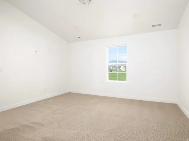 Spacious room featuring neutral carpeting, white walls, and a large window with a mountain backdrop