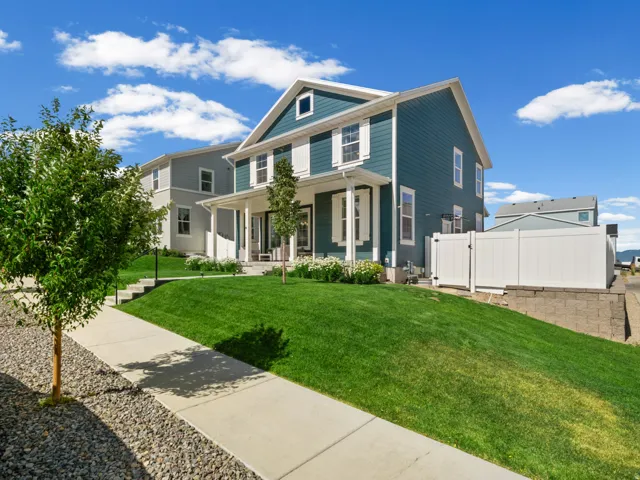 Two-story residence featuring deep teal siding with white trim accents and a covered front porch