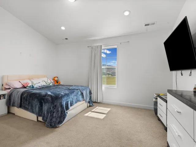 Carpeted room with a vaulted ceiling and recessed lighting