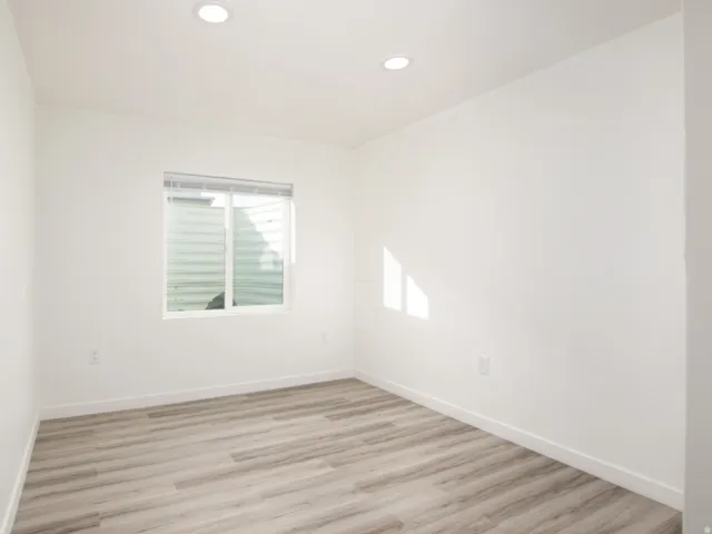 Room featuring wood-finish flooring, recessed lighting, and a window with horizontal blinds