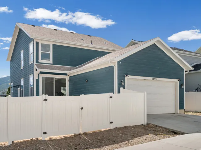Two-story residence featuring a two-car garage with a white panel door and flanking wall sconces
