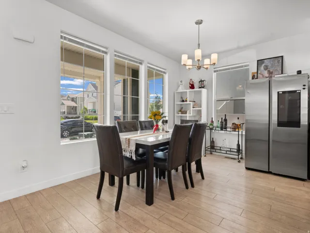 Dining area featuring wood-finish flooring, multiple large windows, and a contemporary chandelier