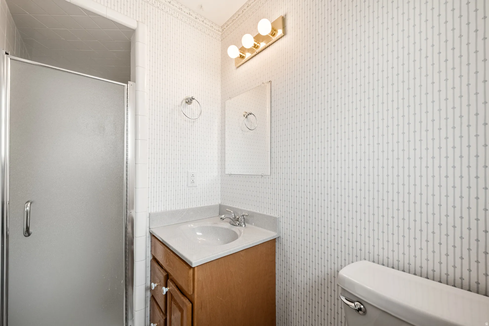 Bathroom vanity featuring a light-toned countertop, integrated sink, and wood cabinetry