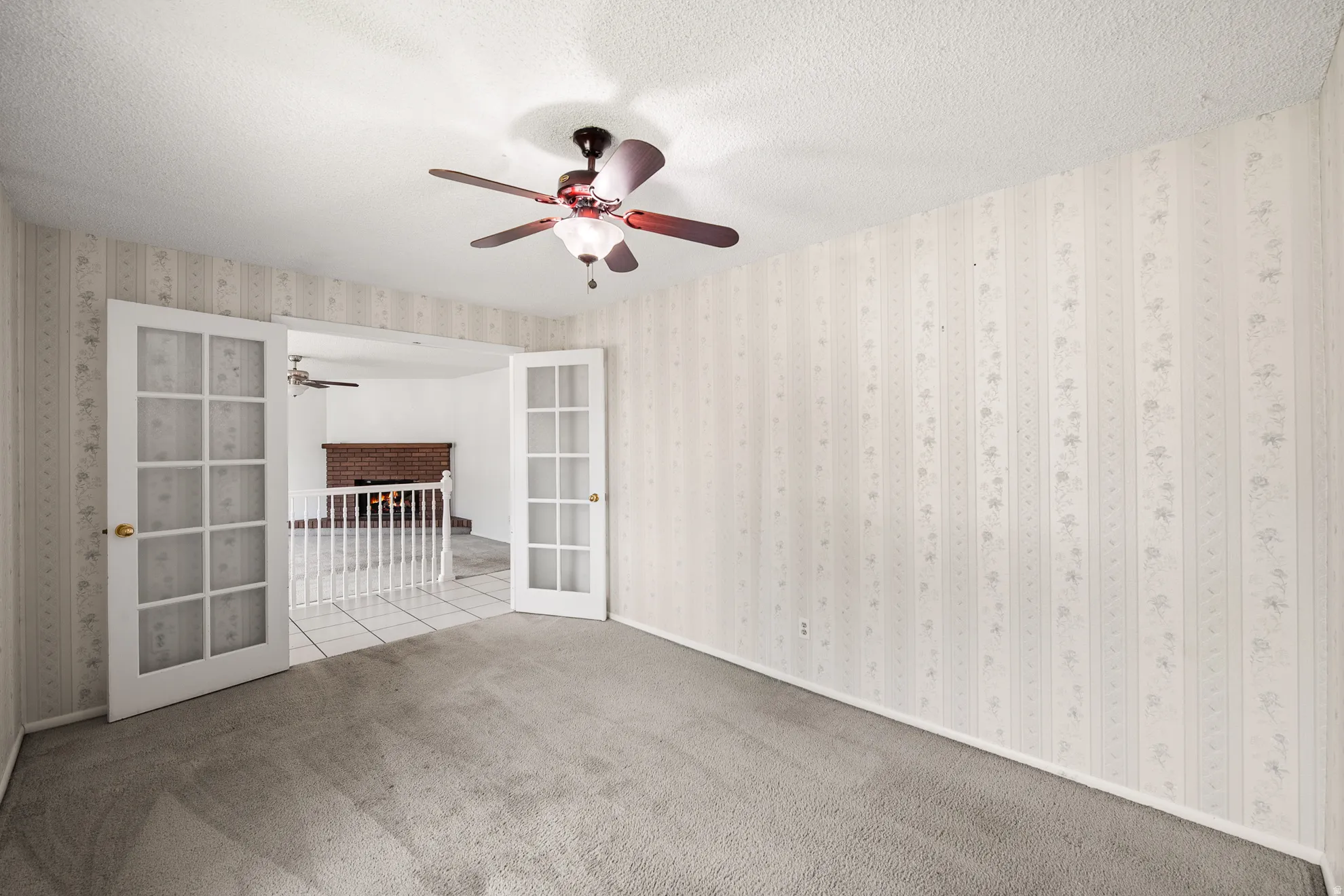 Carpeted interior room featuring French doors opening to a tiled area
