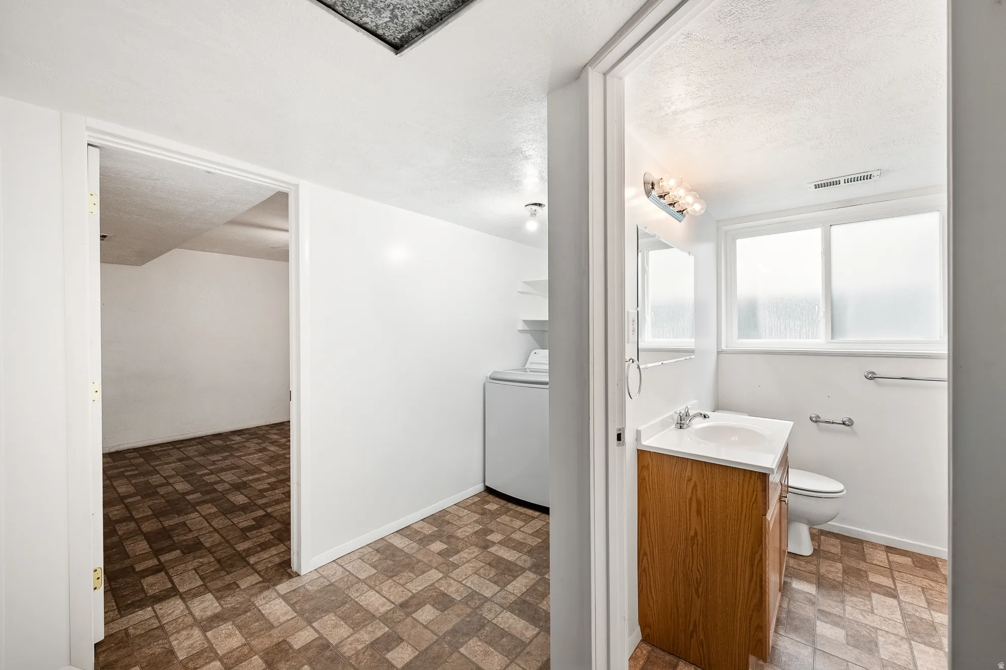 Bathroom featuring a single-sink vanity with wood-finish cabinetry, a white countertop, and a vanity mirror with overhead lighting