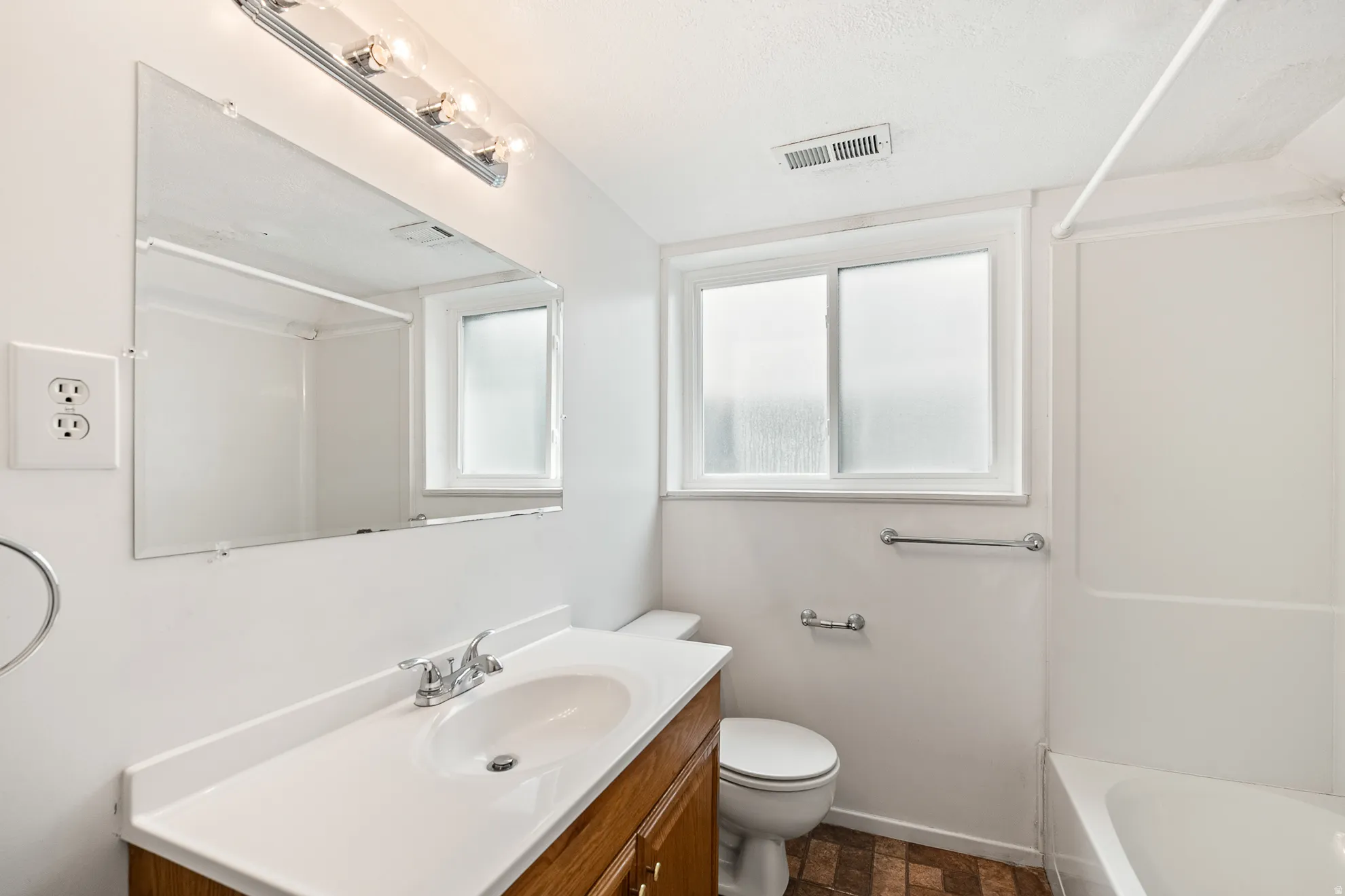 Bathroom featuring a wood-finish vanity with an integrated sink and laminate countertop
