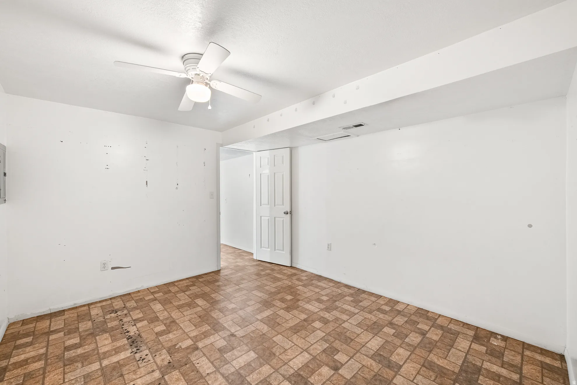 Room featuring white walls, patterned vinyl flooring, and a ceiling fan with integrated lighting