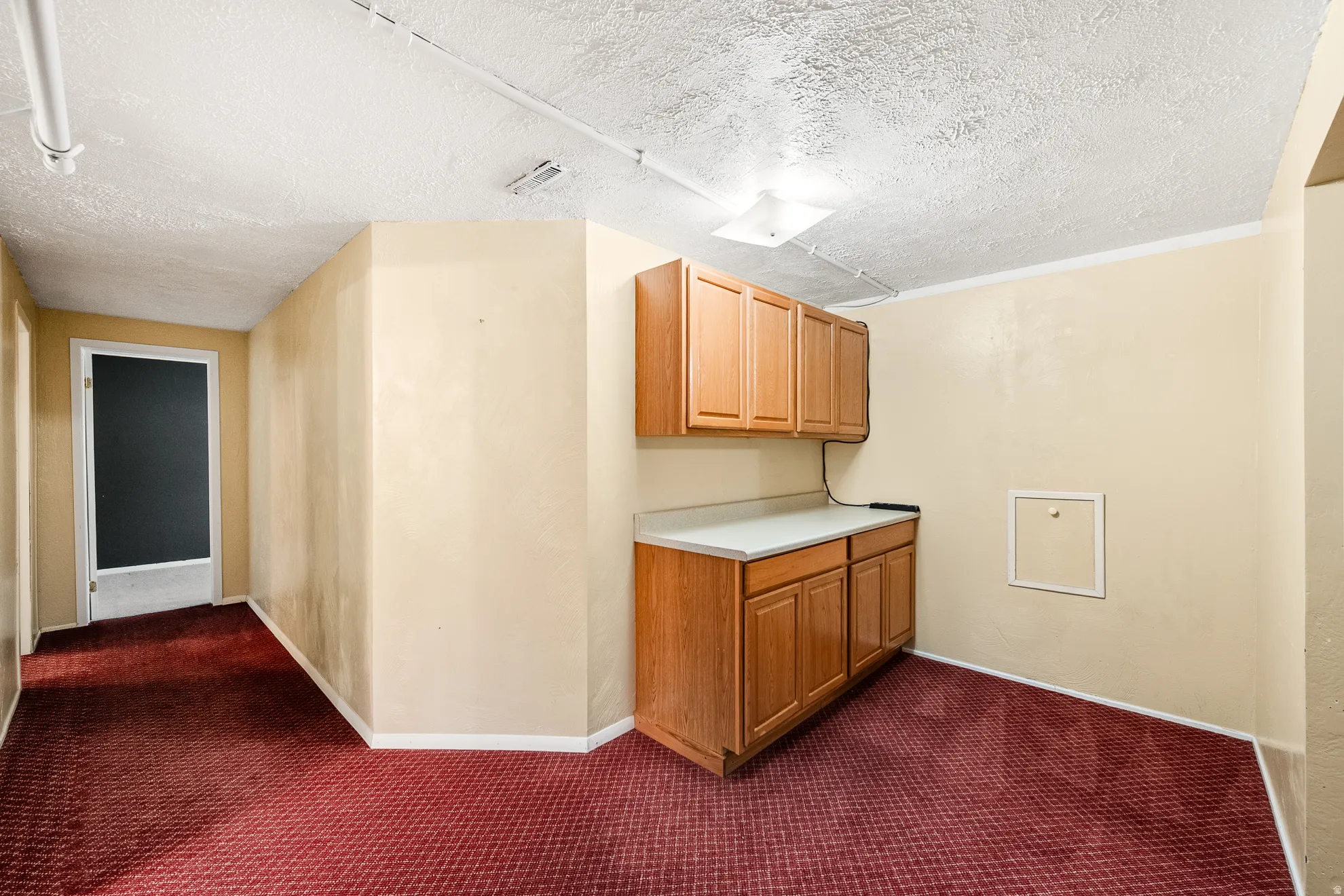 Built-in cabinetry with light wood-finish doors, white countertops, and a textured ceiling