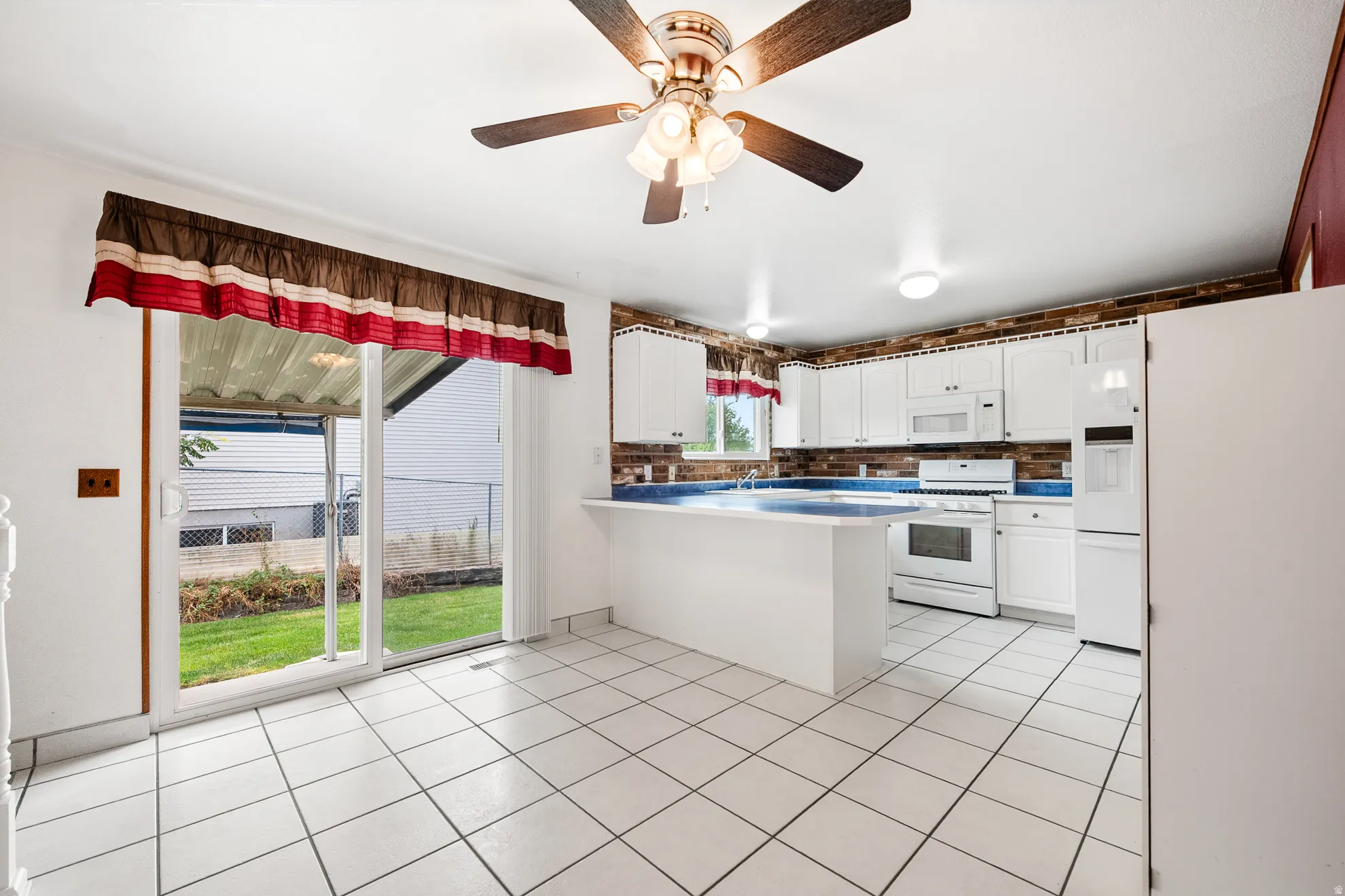 Kitchen featuring white cabinetry, white appliances, a blue countertop, and a brick-patterned backsplash