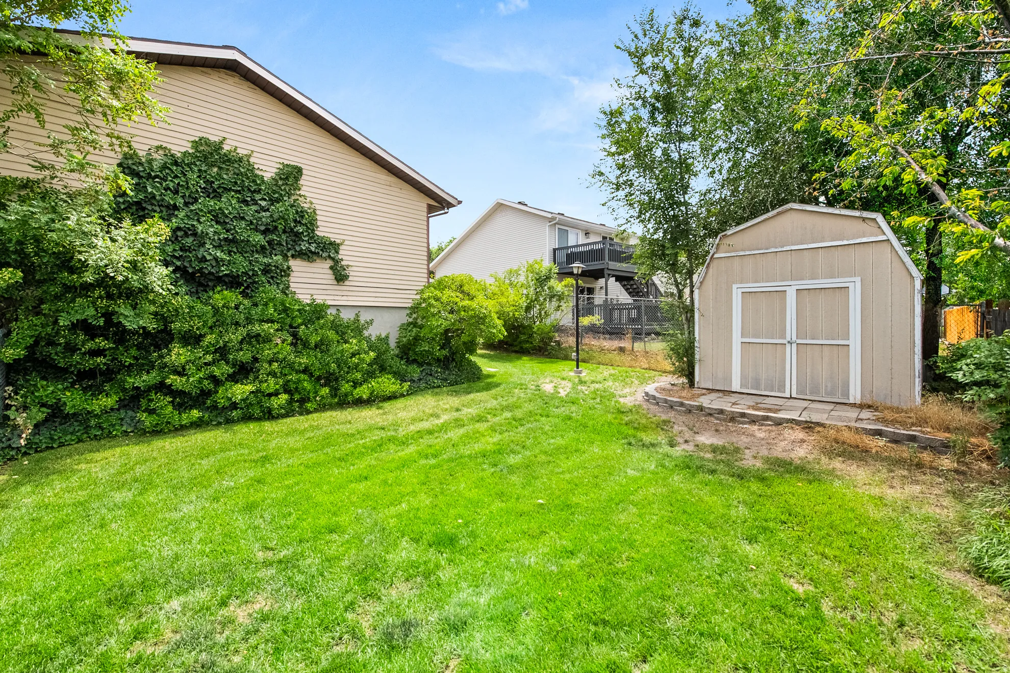 Expansive green lawn with established landscaping and a detached storage shed
