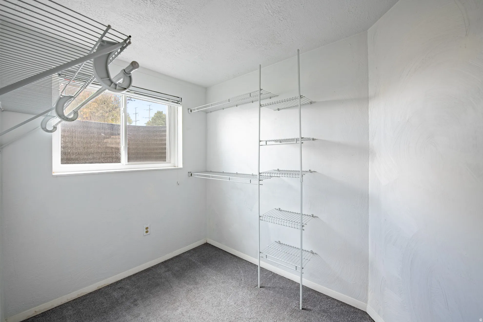 Walk-in closet with wire shelving system, hanging rods, and a double-pane window