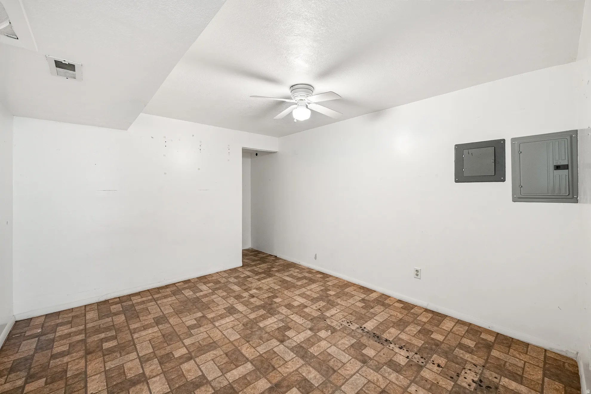 Room featuring patterned floor tile, white walls, and a ceiling fan with light fixture