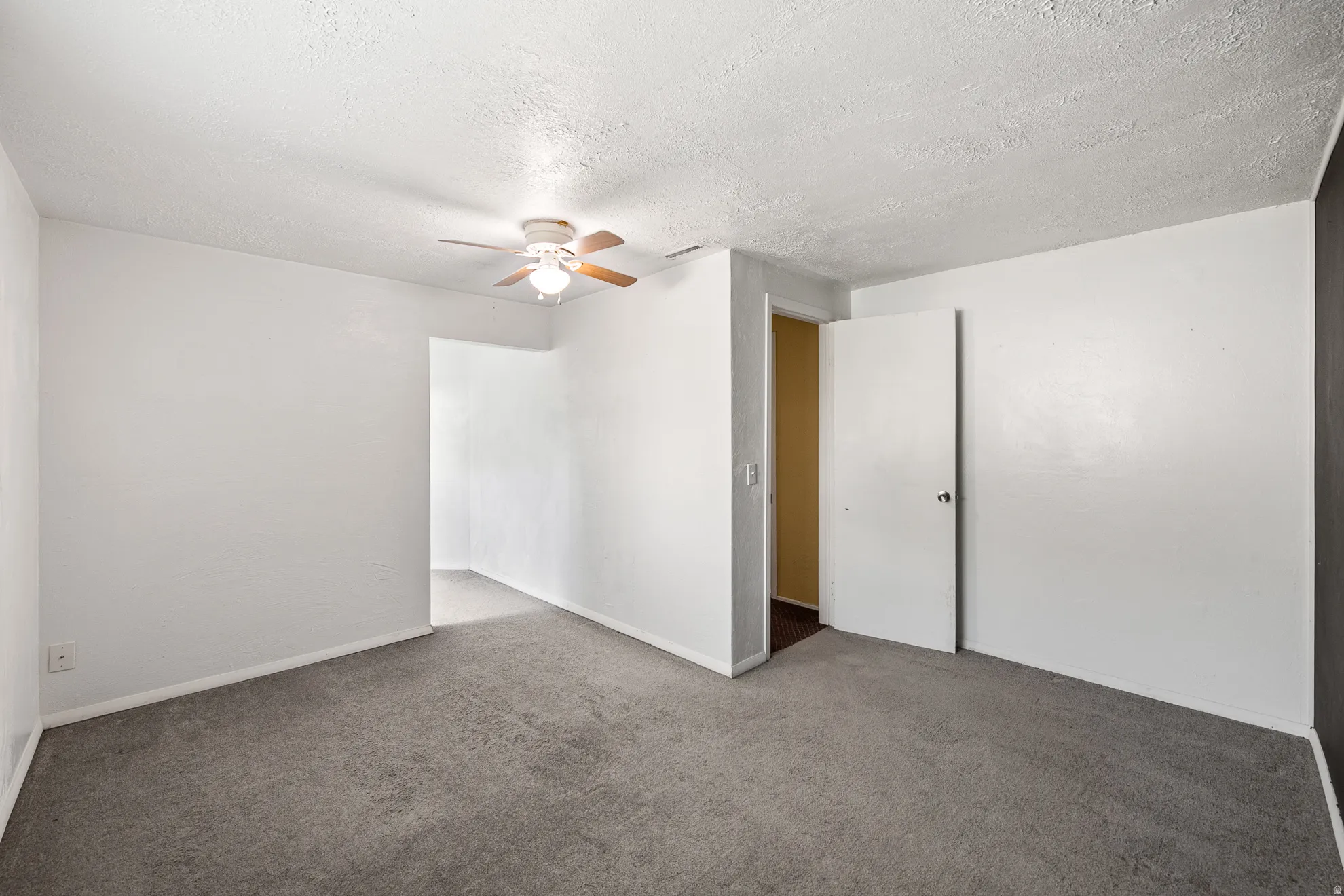 Carpeted interior space with a ceiling fan light fixture, white walls, and white baseboards