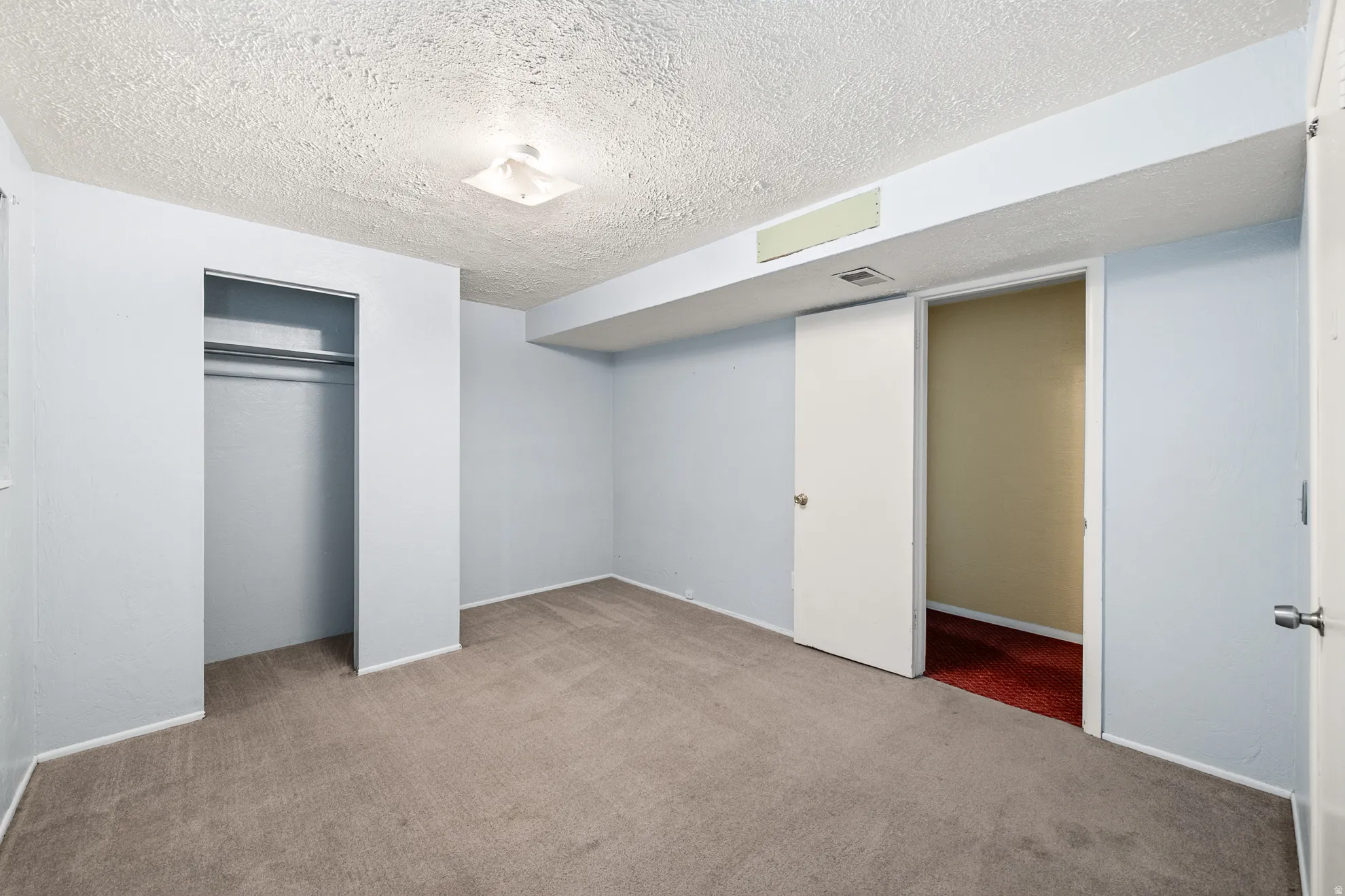 Carpeted room with light blue walls and textured ceiling