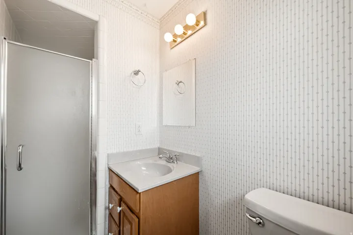 Bathroom vanity featuring a light-toned countertop, integrated sink, and wood cabinetry