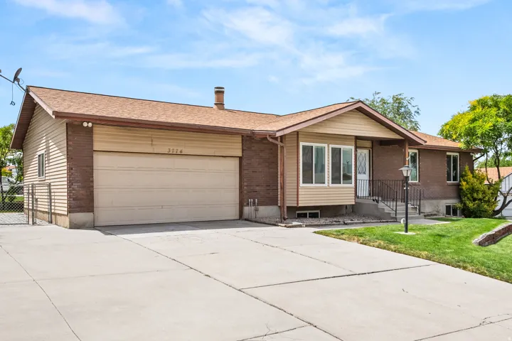 Brick and siding exterior featuring an attached garage with a concrete driveway, a front porch with railing, a front door with a decorative glass insert, and a landscaped lawn