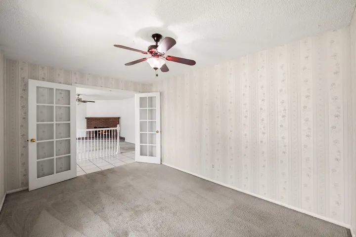 Carpeted interior room featuring French doors opening to a tiled area
