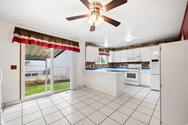 Kitchen featuring white cabinetry, white appliances, a blue countertop, and a brick-patterned backsplash