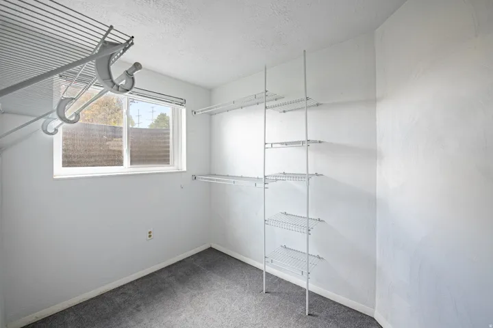 Walk-in closet with wire shelving system, hanging rods, and a double-pane window