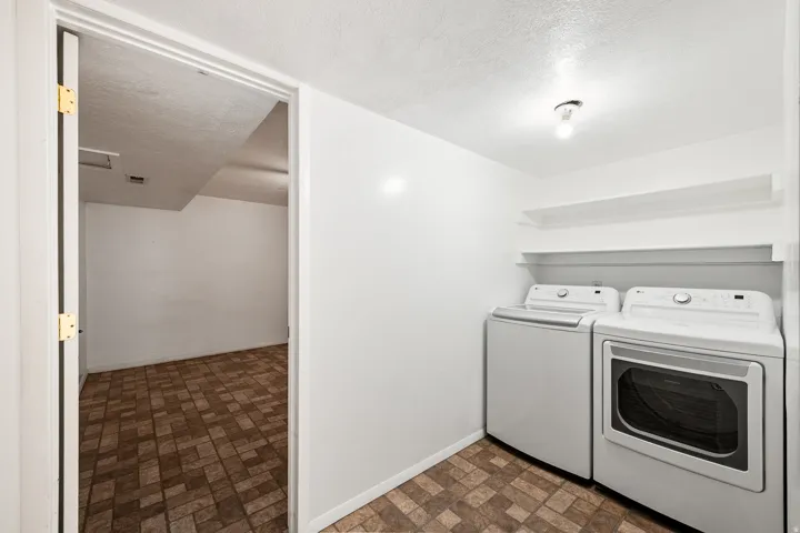 Laundry area featuring a top-load washing machine, front-load dryer, and two wall-mounted shelves