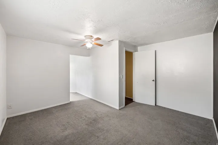 Carpeted interior space with a ceiling fan light fixture, white walls, and white baseboards