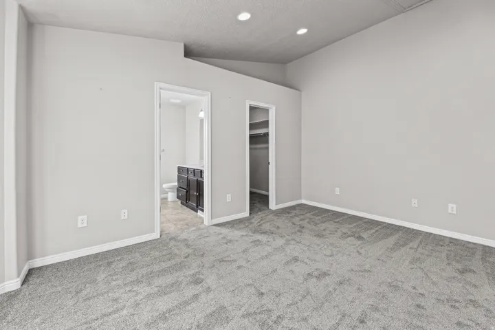 Another view of the primary bedroom highlighting the spacious layout and convenient access to the en-suite bath and walk-in closet.